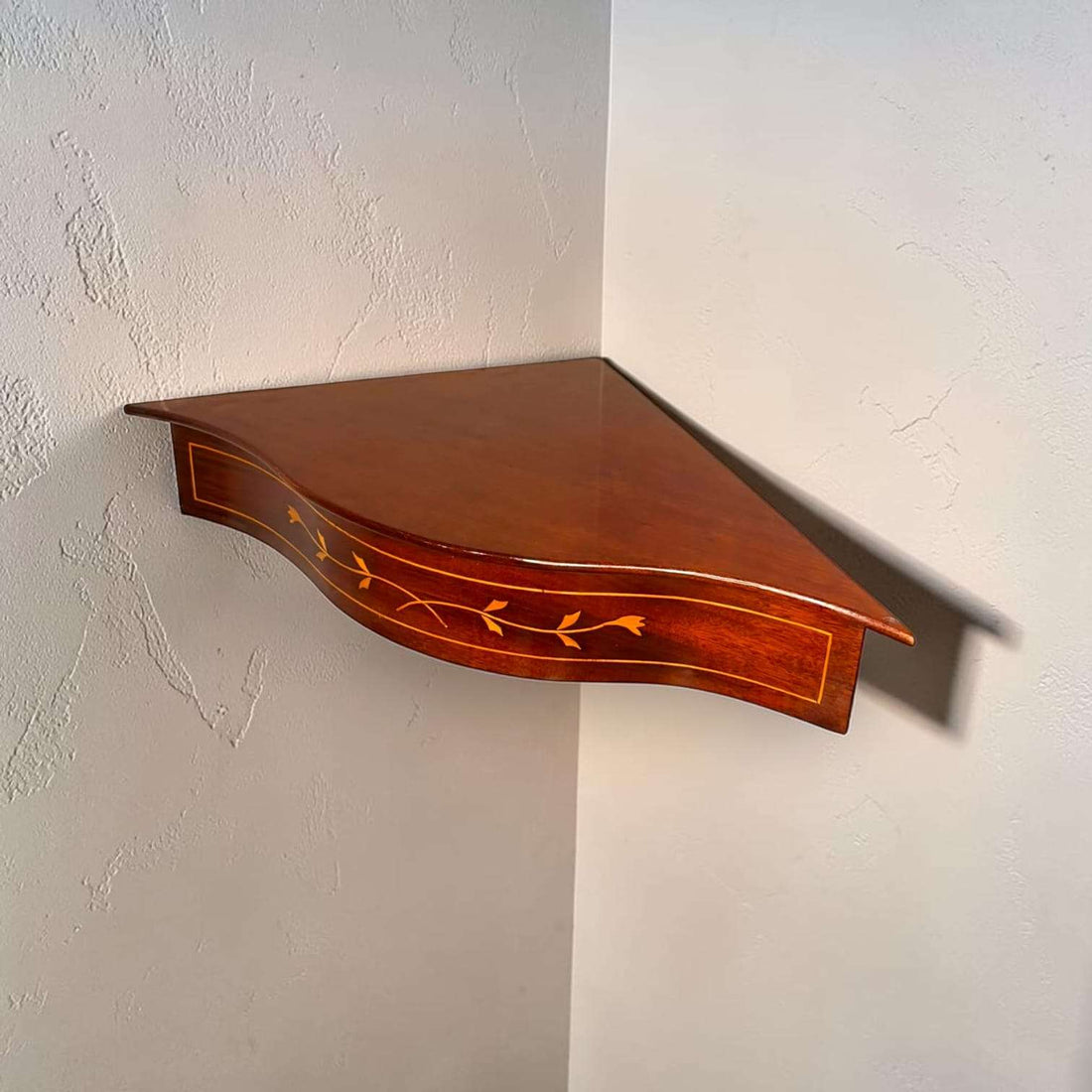 Esta esquinera de pared de caoba ha sido diseñada para aprovechar la unión de dos paredes y convertir un rincón vacío en