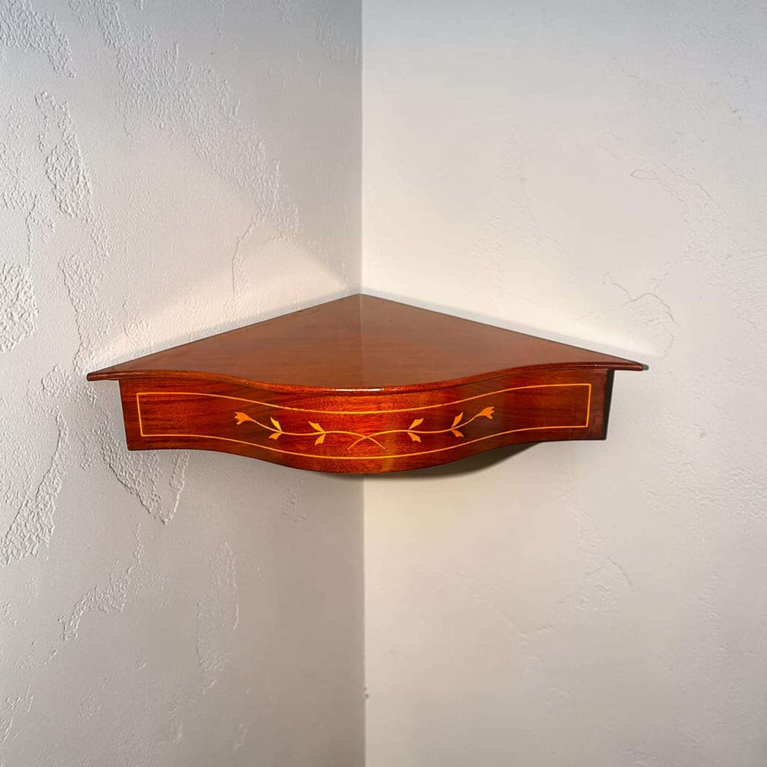 Esta esquinera de pared de caoba ha sido diseñada para aprovechar la unión de dos paredes y convertir un rincón vacío en